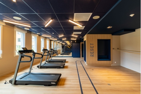 Salle de sport équipée de tapis de course modernes et éclairage LED dans un environnement élégant